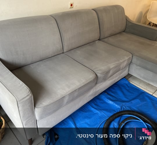ספה אפורה עם צינור ניקוי על יריעת פלסטיק כחולה